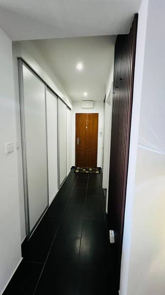 Ein schmaler Flur mit schwarzem Boden und weißen Einbauschränken in einer 3-Zimmer-Wohnung.