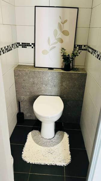 Badezimmer in einer 3-Zimmer-Wohnung mit Toilette, Bild und Pflanze auf der Fensterbank.