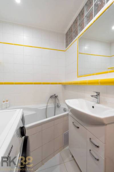 Badezimmer der Ferienwohnung mit Badewanne, Waschbecken, Waschmaschine und weißen Fliesen.