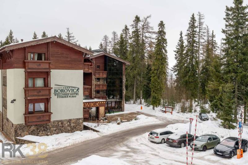 Ferienwohnung in Poprad, umgeben von verschneitem Wald und Parkplätzen.