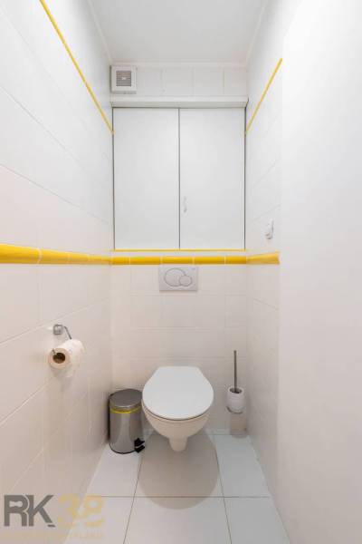 Badezimmer mit weißen Fliesen und gelben Details im Ferienapartment.