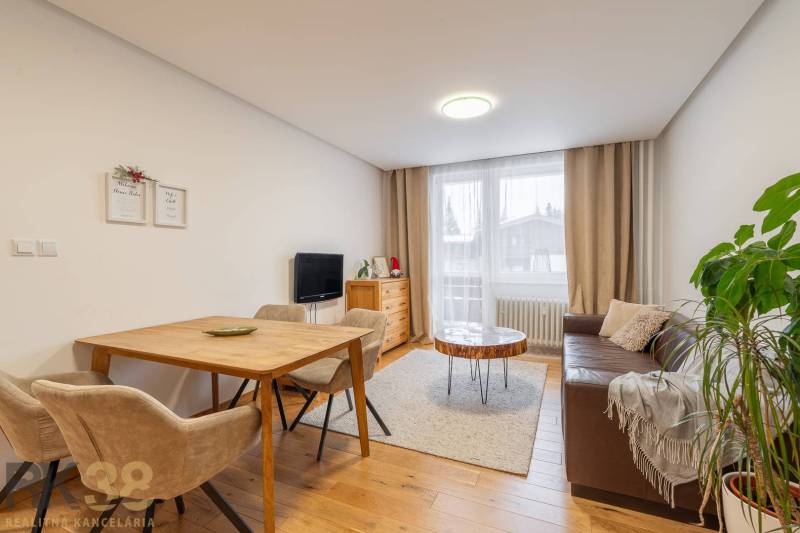 Wohnzimmer in einer Ferienwohnung mit einem gemütlichen Sofa und einem Boden in Holzoptik.