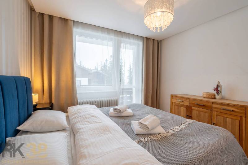 Schlafzimmer in einer Ferienwohnung mit Doppelbett und Kommode, Fenster mit Aussicht.