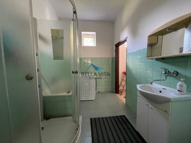 Kúpeľňa v rodinnom dome s priestranným sprchovacím kútom a zelenými obkladačkami.