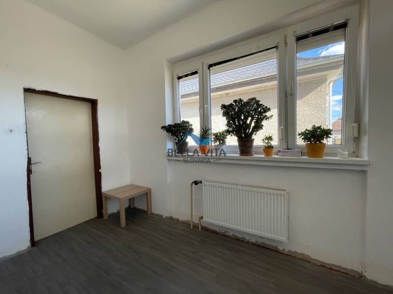 Interiér rodinného domu s podlahou s dreveným dekorom, rastlinami na parapete.