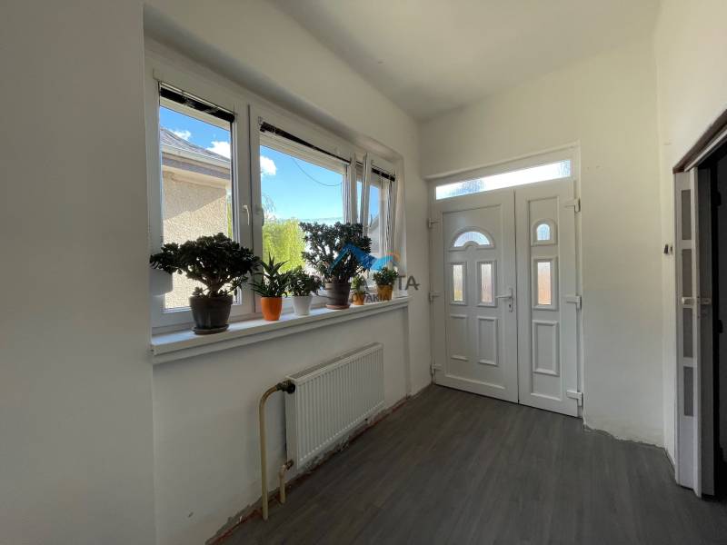 Vstupná hala v rodinnom dome s podlahou s dreveným dekorom a rastlinami na parapete.