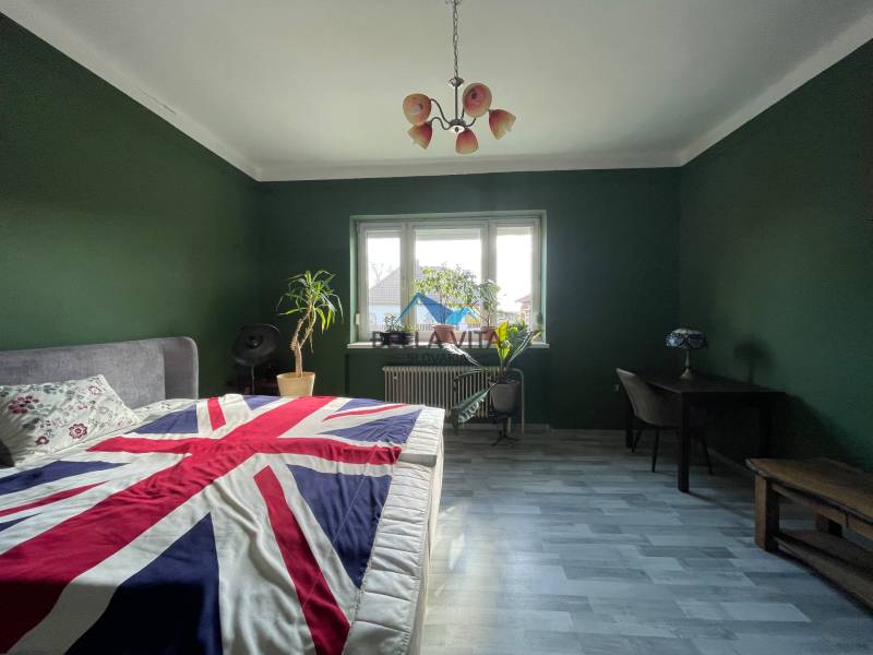 Spálňa v Rodinnom dome s tmavozelenými stenami a posteľou s britskou vlajkou.