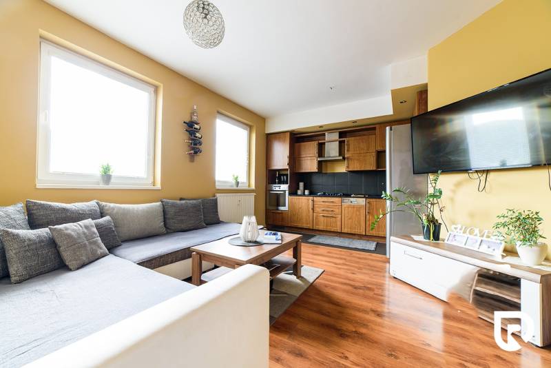 Wohnzimmer in einer 2-Zimmer-Wohnung mit Küchenzeile und Holzboden.