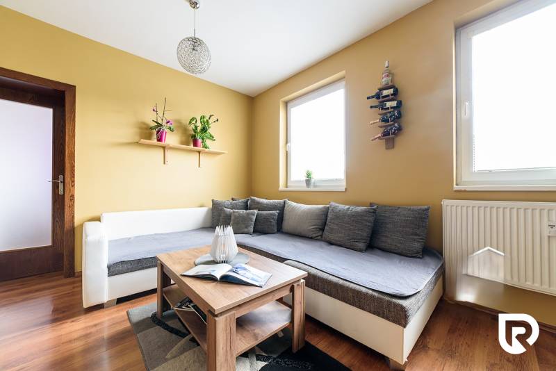 Wohnzimmer in einer 2-Zimmer-Wohnung mit Holzboden und bequemen Sitzgelegenheiten.