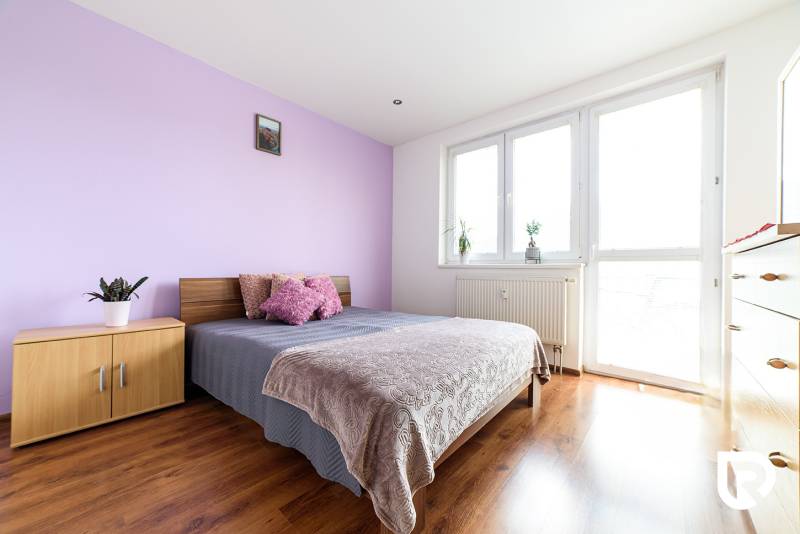 Schlafzimmer in einer 2-Zimmer-Wohnung mit Bett, Schrank und Boden in Holzoptik.