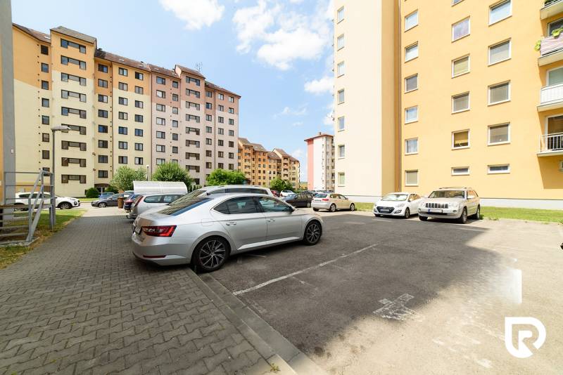 Parkplatz in der Armádna-Straße in Trenčín mit geparkten Autos vor Wohnhäusern.