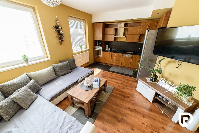 Wohnzimmer mit Holzboden, Sofa und Küchenzeile in einer Zweizimmerwohnung.