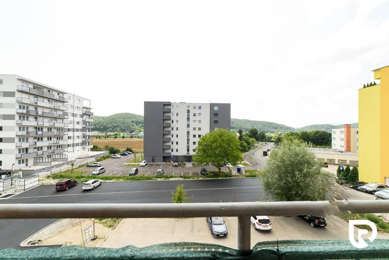 Blick vom Balkon in der Armádna-Straße in Trenčín, umgeben von Grün und Gebäuden.