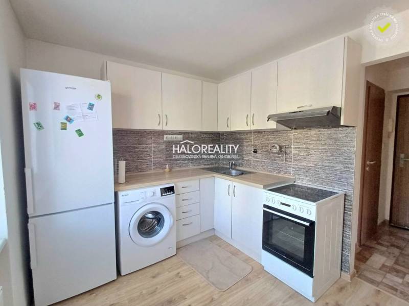 Küche in einer Einzimmerwohnung mit weißen Schränken und Holzboden.