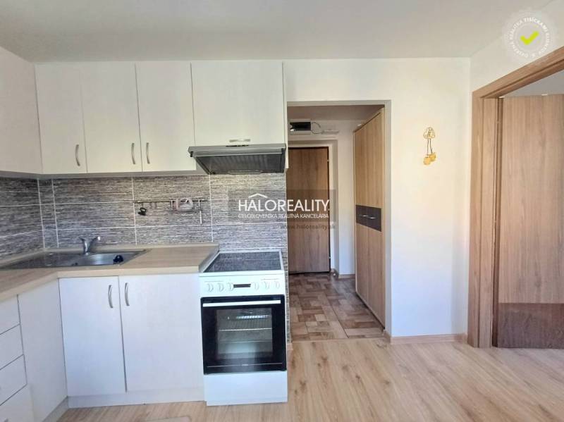 Küchenzeile mit weißen Schränken und Bodenbelag in Holzoptik in einer Einzimmerwohnung.