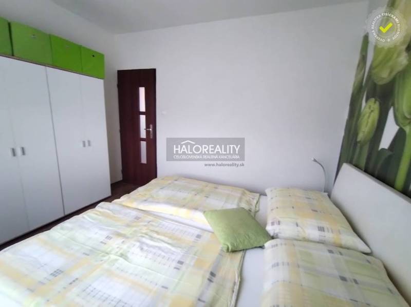 Schlafzimmer in einer 4-Zimmer-Wohnung mit Bett, Schrank und dekorativer Wand mit Blume.