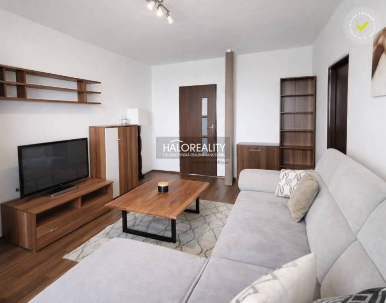 Wohnzimmer mit Holzboden, Sofa und Fernseher in einer Vierzimmerwohnung.