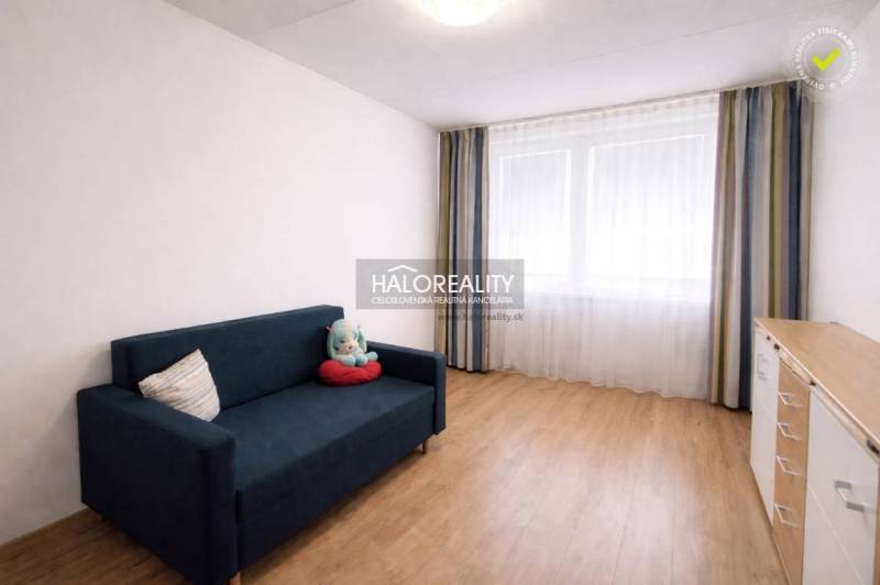 Ein Zimmer in einer 4-Zimmer-Wohnung mit einem blauen Sofa und einem Boden in Holzoptik.