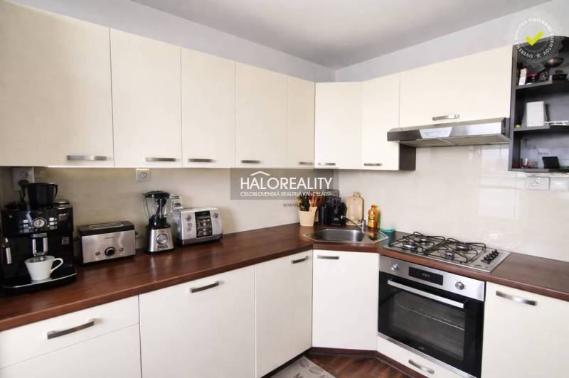 Küche in einer 4-Zimmer-Wohnung mit weißen Schränken und einem Boden in Holzoptik.