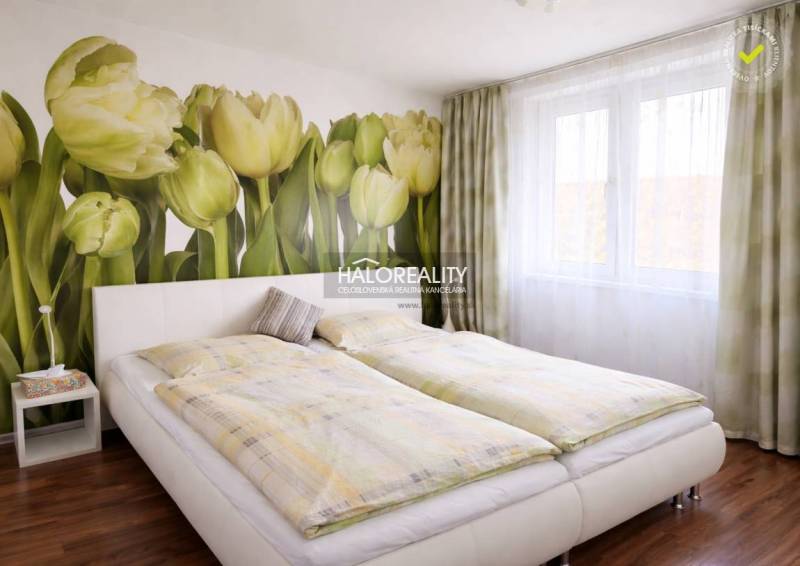 Schlafzimmer in einer 4-Zimmer-Wohnung mit Tapete mit Tulpenmotiv und einem Bett auf dem Boden mit Holzdekor.
