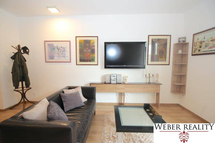 Wohnzimmer in einer Einzimmerwohnung mit schwarzem Sofa und Holzboden-Dekor.