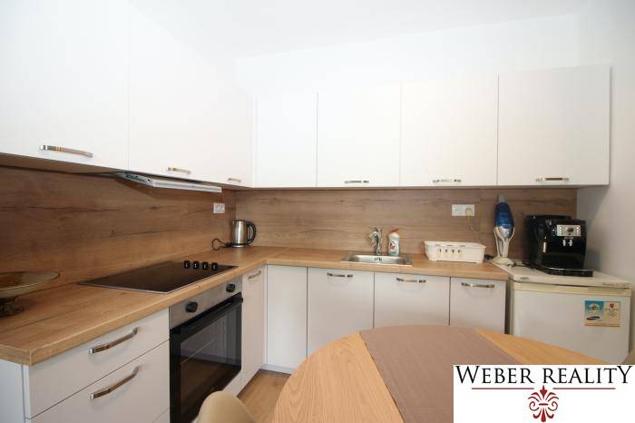 Küche mit eingebauten Geräten und Holzelementen in einer Einzimmerwohnung.
