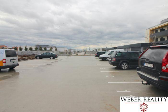 Parkplatz in der Broskyňová-Straße in der Stadt Rovinka mit Autos und Wohngebäuden im Hintergrund.