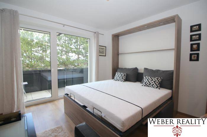 1-Zimmer-Wohnung mit Blick auf den Balkon und einem Bett in der intelligenten Wand.