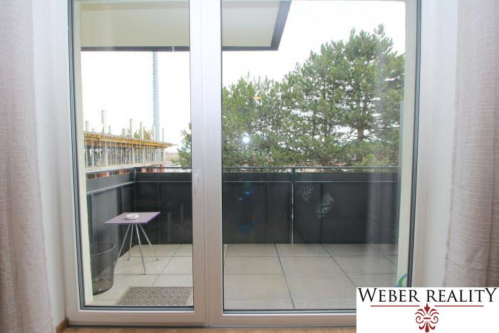 Balkon mit Schiebetüren und Blick auf Bäume in einer Einzimmerwohnung in der Broskyňová-Straße in Rovinka.