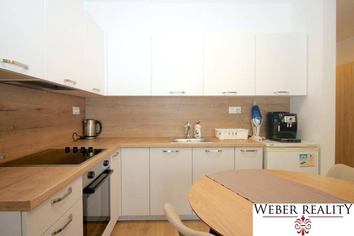 Weiße Küche mit Holzdekor in einer Einzimmerwohnung mit Geräten.