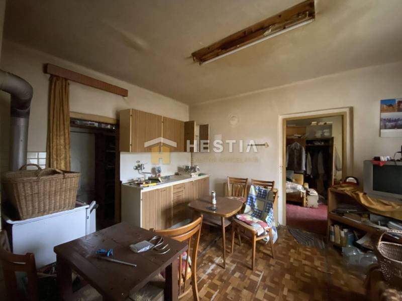 Küche in einem Einfamilienhaus mit Holzmöbeln, einem alten Fernseher, einem Esstisch und einem Kleiderschrank.