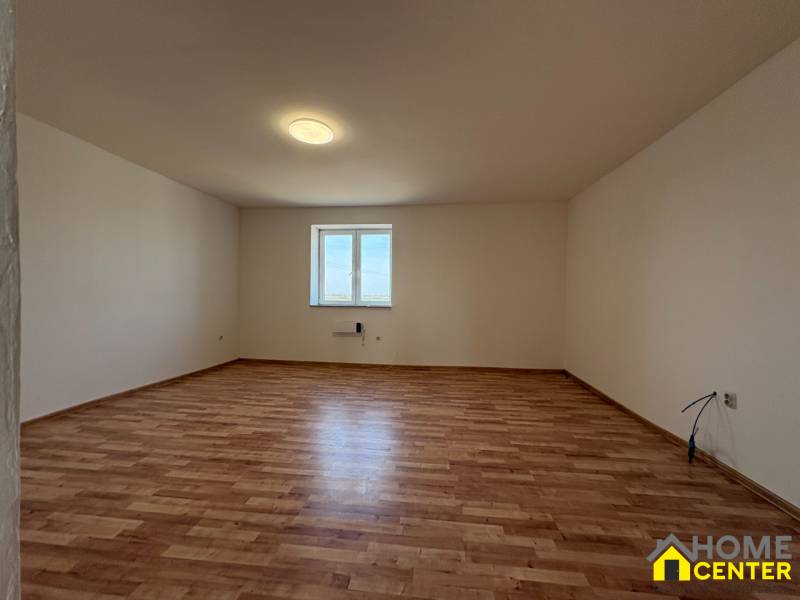Geräumiger Raum mit Fenster und Holzboden in einem Einfamilienhaus.