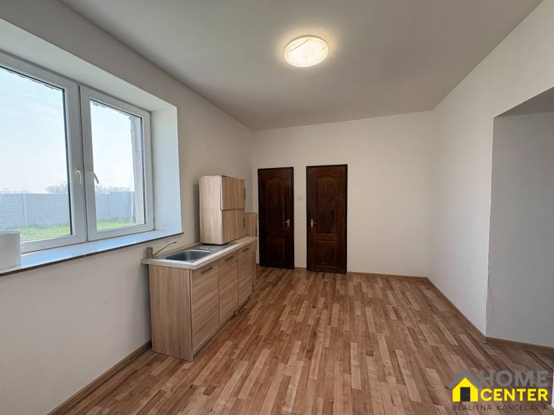 Ein Zimmer mit Küchenzeile, Holzboden, zwei Holztüren.