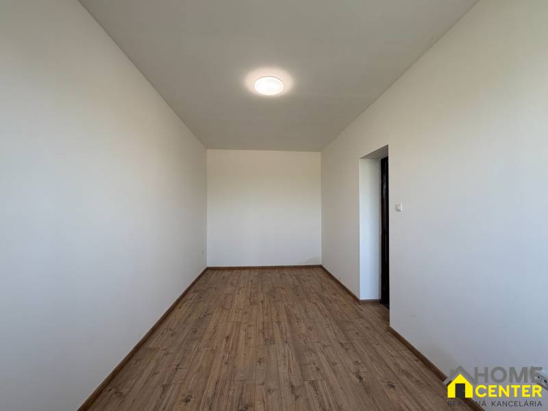 Ein Einfamilienhaus mit weißen Wänden und einem Boden in Holzoptik.