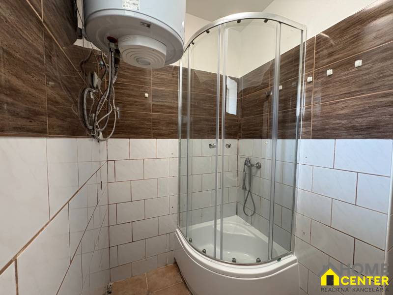 Badezimmer in einem Einfamilienhaus mit Eckdusche, elektrischem Boiler und braunen Fliesen.