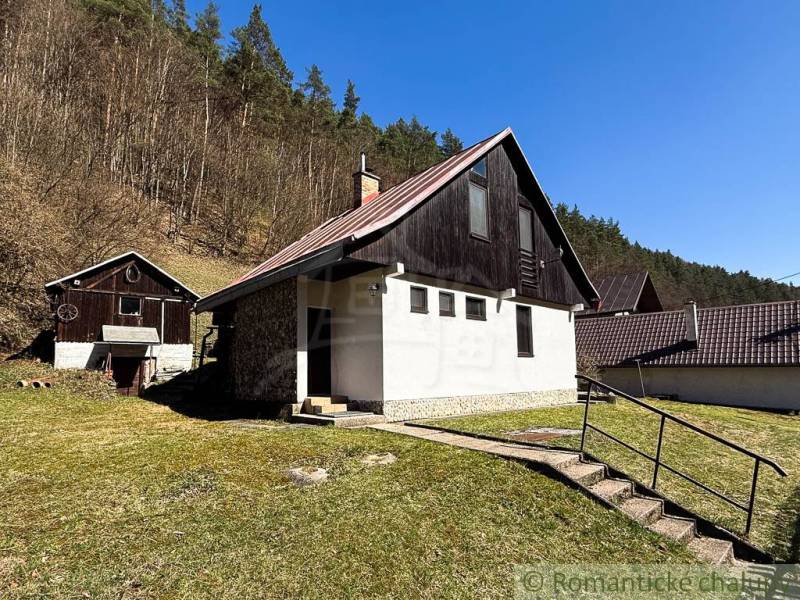 Eine Hütte in Moštenica, umgeben von Natur und Wald, mit klarem Himmel und einer grasbewachsenen Fläche.
