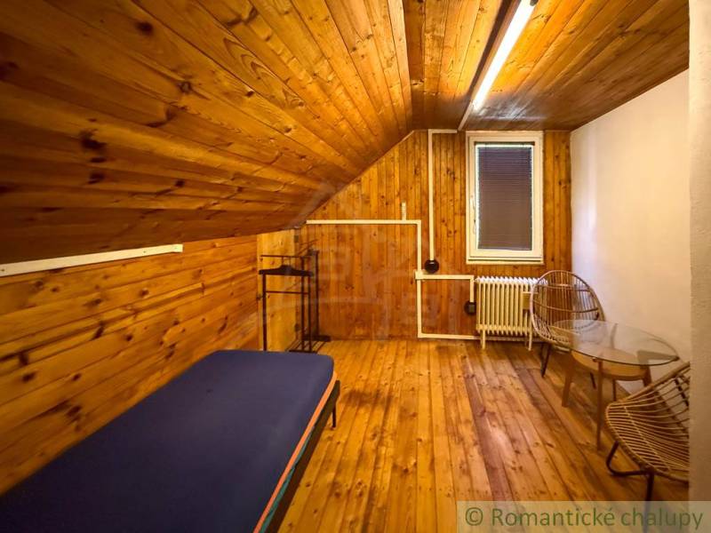 Innenraum einer Hütte mit Holzboden, Bett und Stühlen für Komfort.