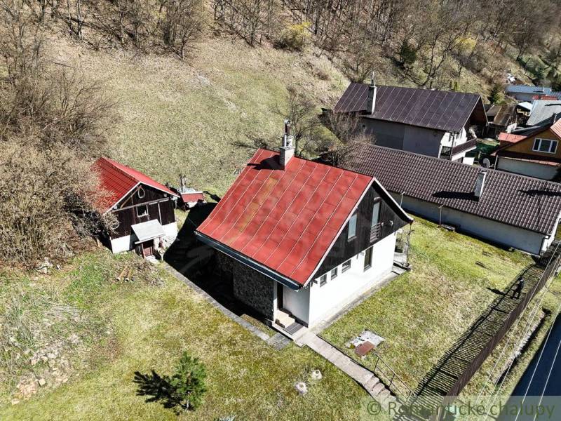 Eine Hütte in Moštenica mit einem schrägen roten Dach, umgeben von Grün und hügeligem Gelände.