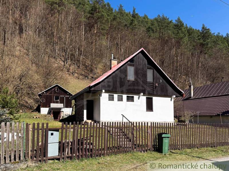Eine Hütte in Moštenica, umgeben von Wäldern, mit einem Zaun und einem Mülleimer im Hof.
