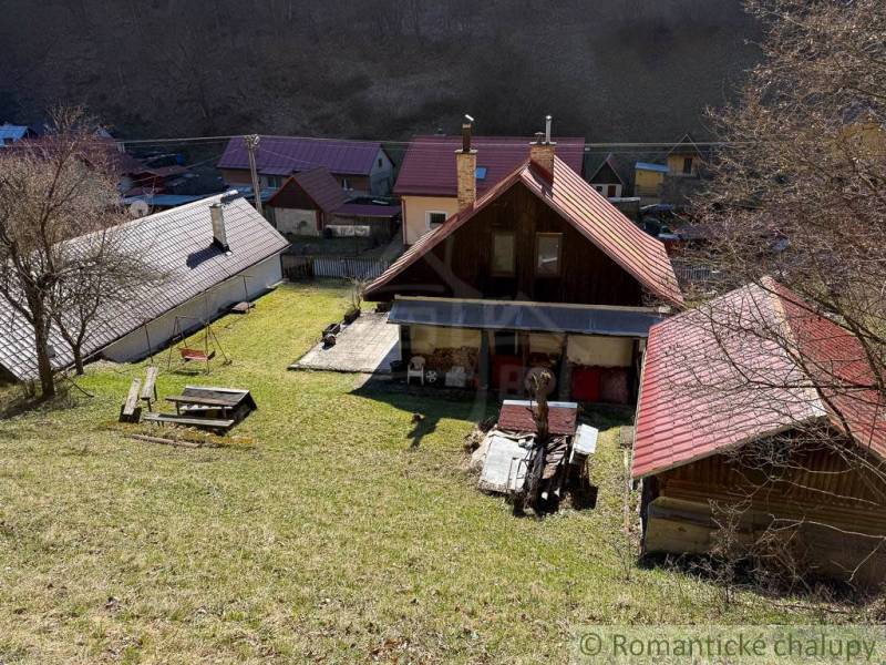 Eine Hütte in Moštenica, umgeben von Rasen und Bäumen.