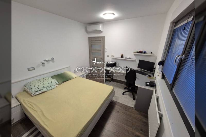 Schlafzimmer im Einfamilienhaus mit Schreibtisch und Boden in Holzoptik.