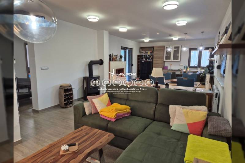 Wohnzimmer eines Einfamilienhauses mit Kamin, Sofa und Küchenzeile.