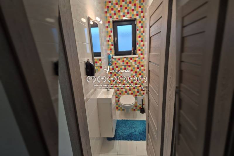 Buntes Badezimmer mit Fliesen und blauem Teppich in einem Einfamilienhaus.