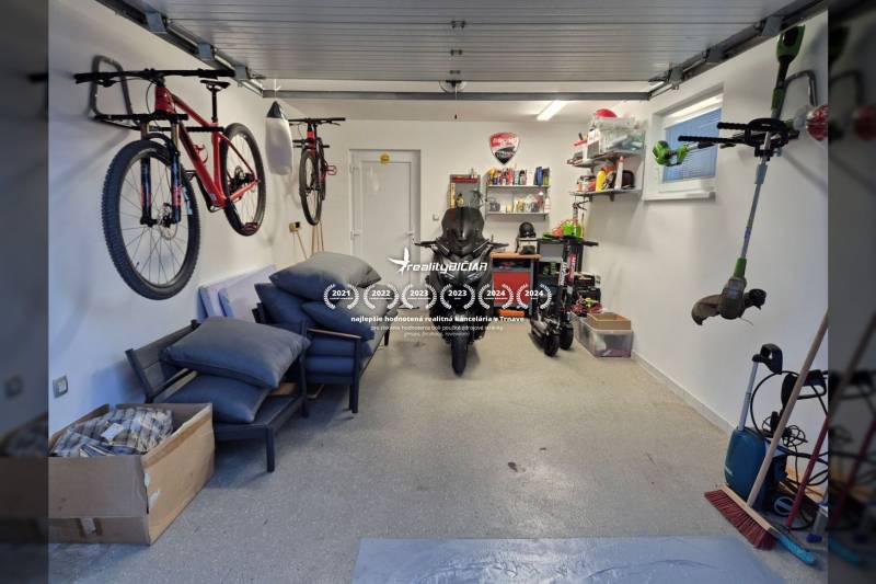 Die Garage des Einfamilienhauses mit Fahrrädern, einem Motorrad und Regalen mit Werkzeugen und Zubehör.