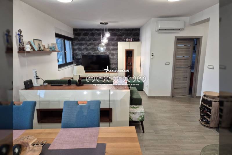 Wohnzimmer mit Fernseher, Holzboden, Sofa und dekorative Wand.