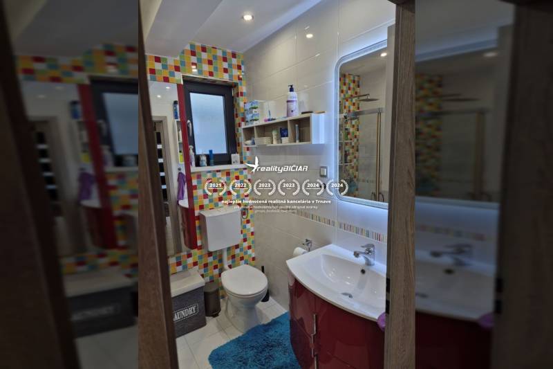 Ein Badezimmer in einem Einfamilienhaus mit farbigen Fliesen und hellen Wänden.