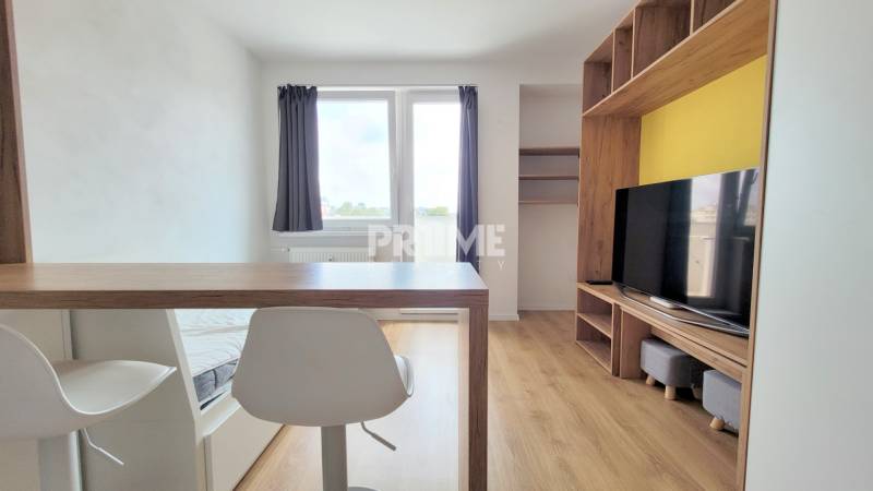 Einzimmerwohnung mit Holzboden, Fernseher und Esstheke.