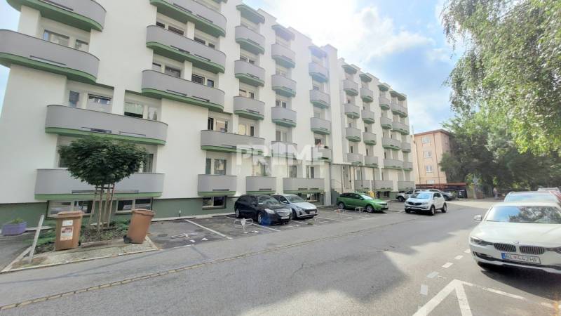 Parkplatz und Wohnhäuser in der Ondavská Straße in Bratislava - Ružinov, umgeben von Grünflächen.