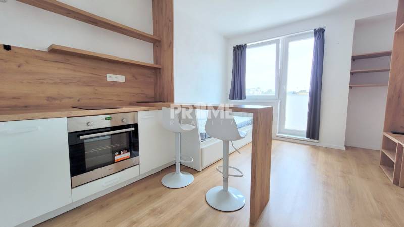 Einzimmerwohnung mit Küchenzeile, Stühlen und Boden in Holzoptik.