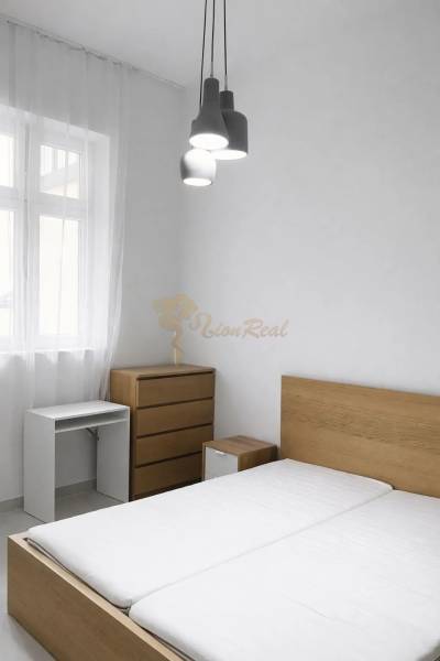 Schlafzimmer mit Holzmöbeln und Hängelampen in einer Zweizimmerwohnung.